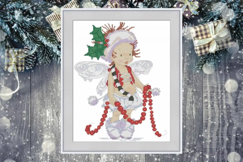Cross stitch pattern of a Christmas fairy with holly leaves, wings, and a red garland, detailed festive embroidery design on white background.