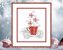 Cross stitch pattern of a red cup in hands with falling snowflakes, cozy winter embroidery design on white background.
